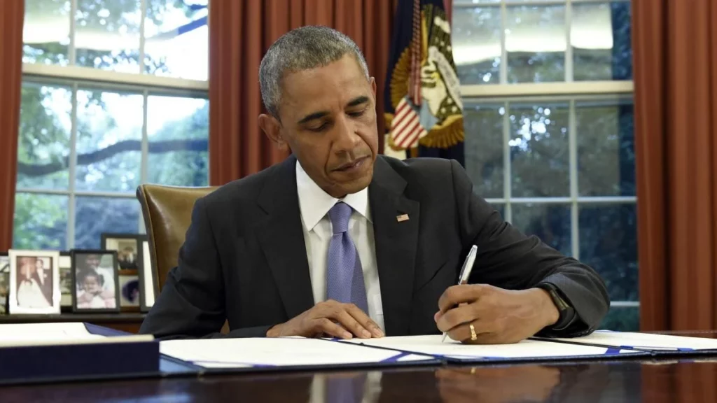 Barak Obama firmando un documento en su oficina, en la Casa Blanca